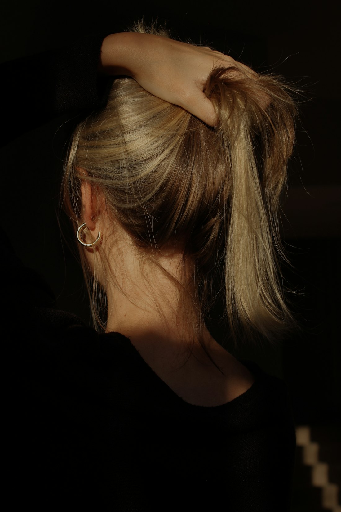 Frau bindet ihr blondes Haar zusammen, von hinten fotografiert